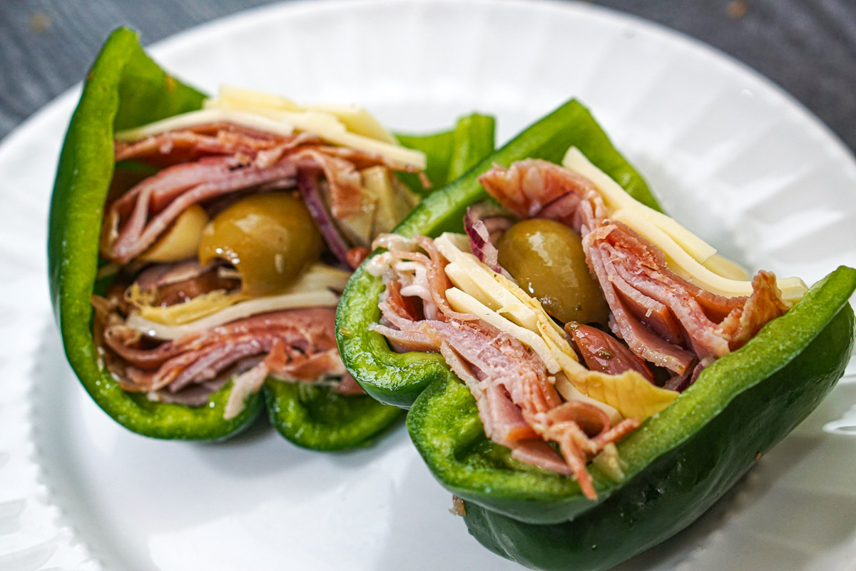 Closeup of a green bell pepper stuffed with meats, cheeses, olives and artichokes.