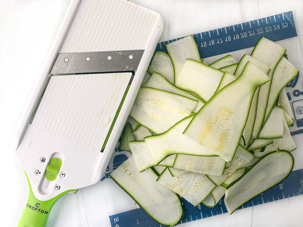 hand mandoline and sliced zucchini and cutting board