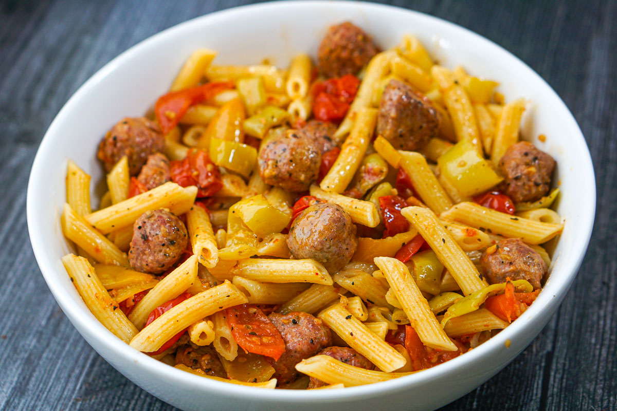 white bowl with finish penne, sausage and banana peppers