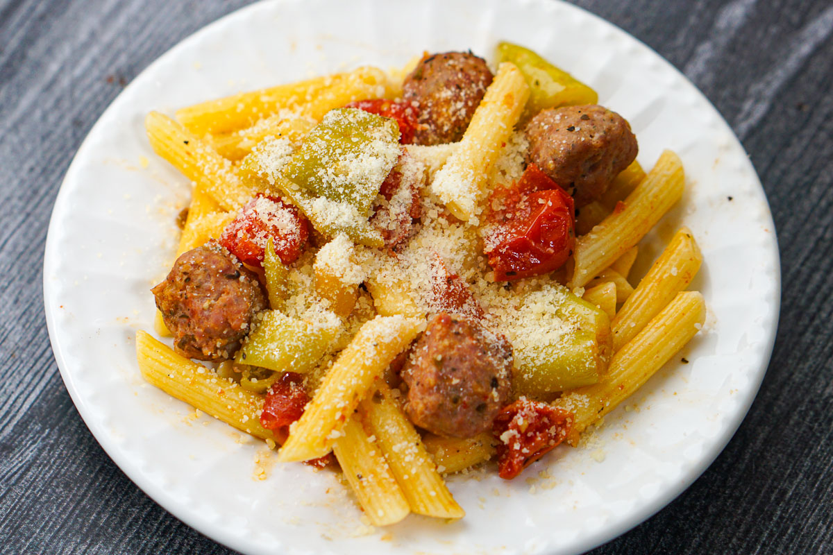 closeup of a white plate with pasta topped with parmesan cheese