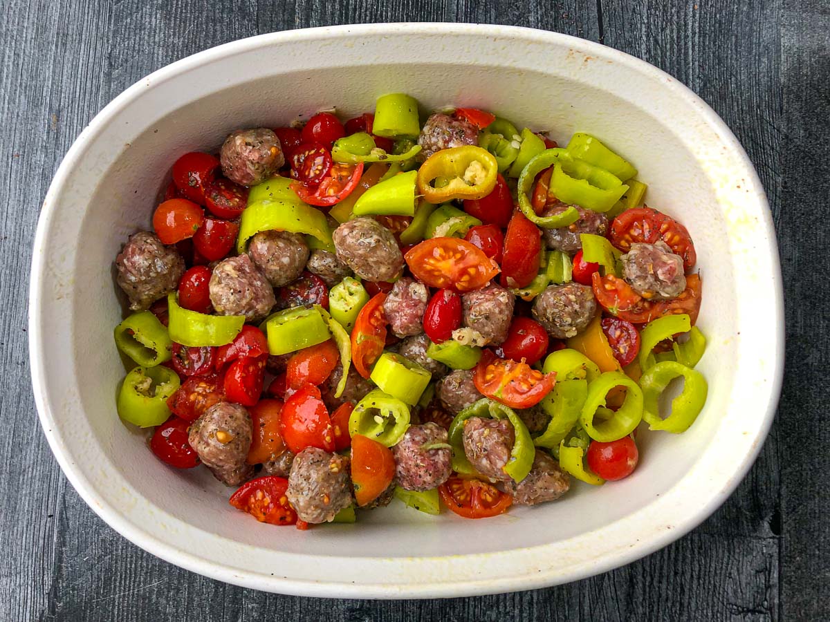white baking dish with meatballs and chopped peppers ready to bake