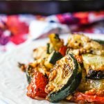 closeup of roasted zucchini and tomatoes with floral tea towel