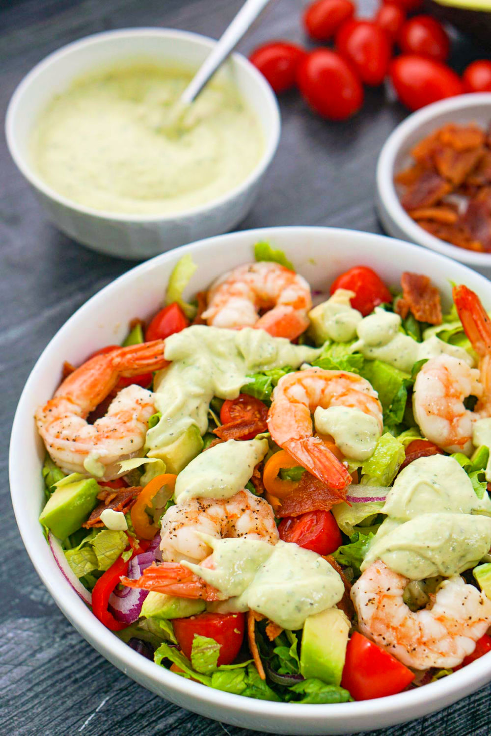 white bowl with keto shrimp and avocado salad and dressing in background