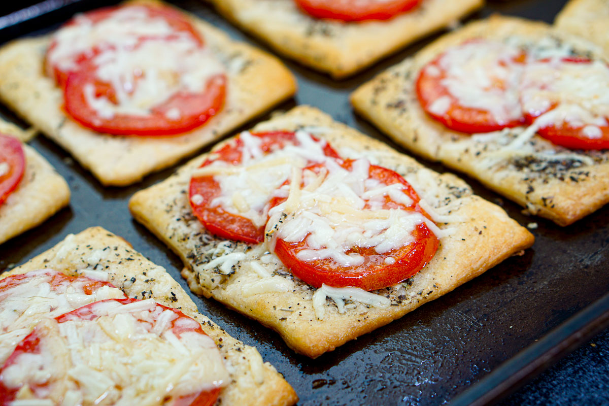 closeup of a pan of fresh tomato tarts with melted parmesan cheese