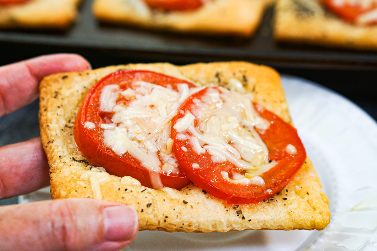 fingers holding tomato crescent bread