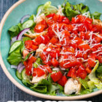 Aqua bowl with a big protein bruschetta salad with chicken and text.