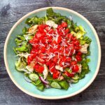 Aerial view of a aqua bowl with a high protein bruschetta salad with chicken.