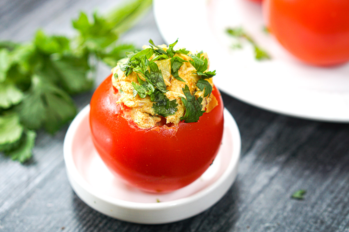 closeup of a tomato stuffed with curry chicken salad and fresh cilantro