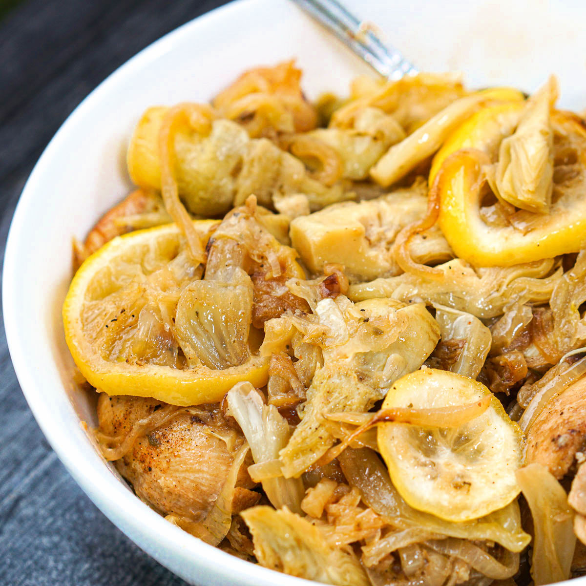 closeup of a white bowl with chicken artichokes and fennel dish