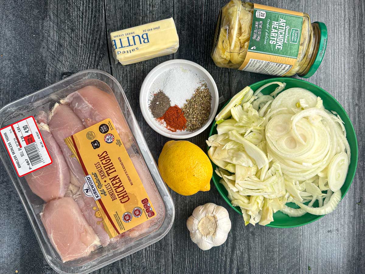 recipe ingredients - chicken thighs, lemon, spices, garlic, butter, fennel slices and artichokes