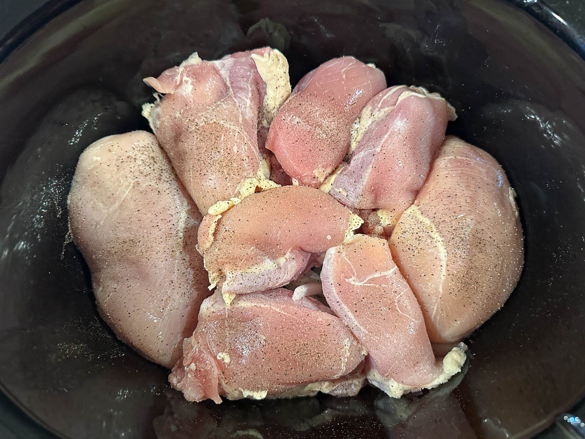 crockpot with raw onions and chicken pieces