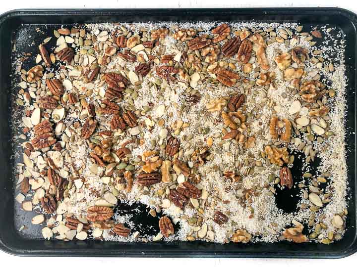 cookie sheet with uncooked nuts and seeds and coconut