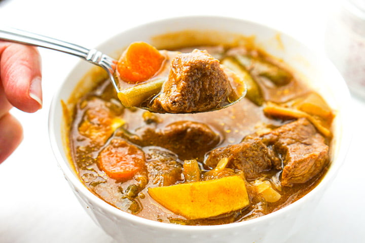 a spoonful of stew with a piece of carrot and a chunk of beef