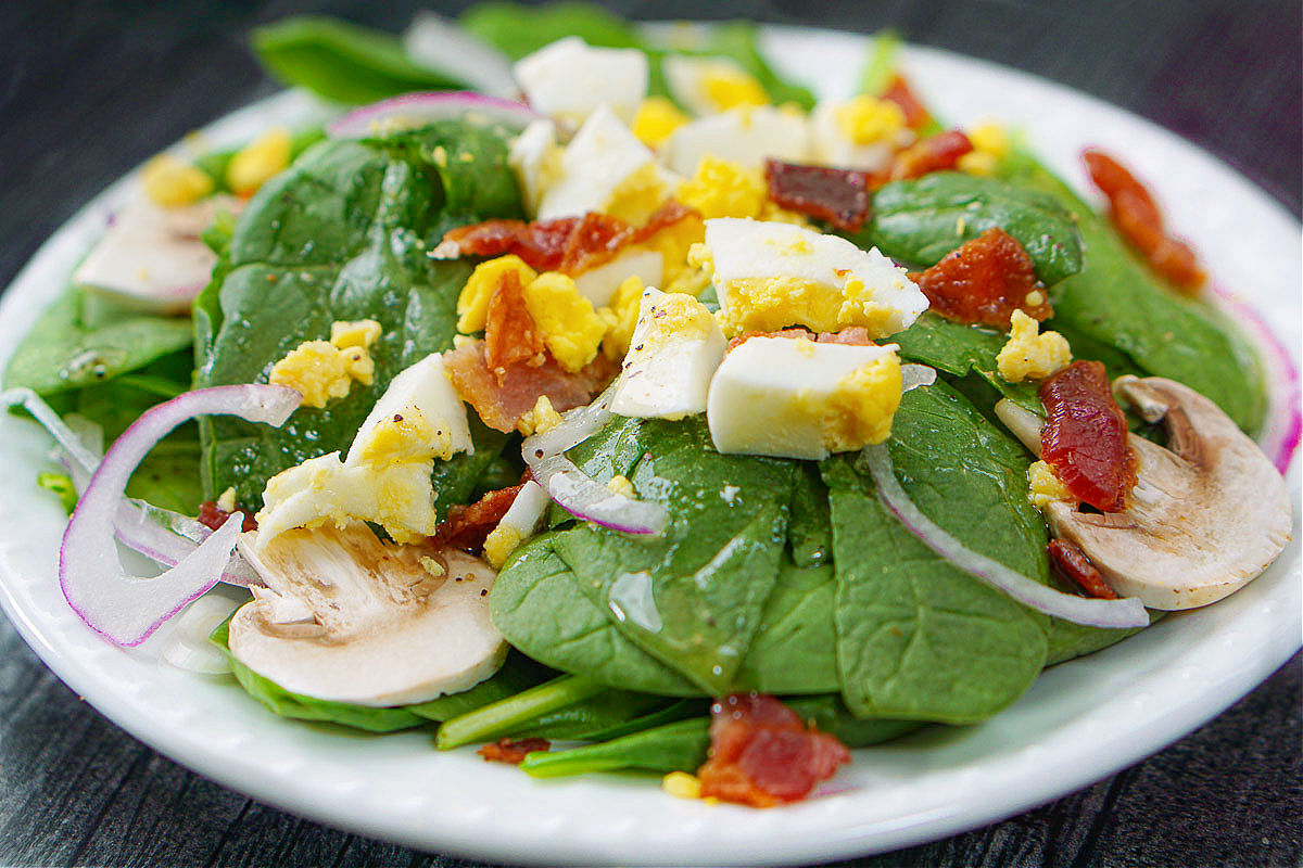 closeup of a white plate with spinach salad