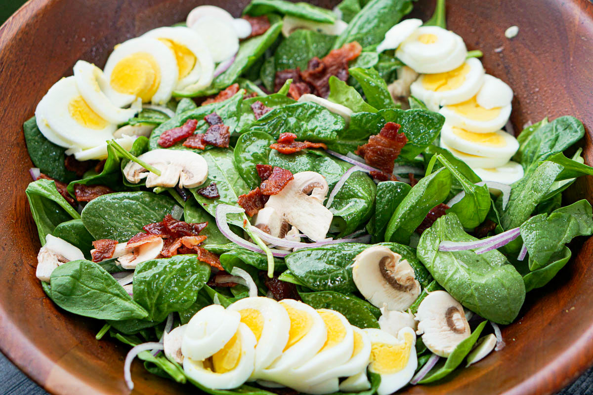 closeup of a big wooden salad bowl with spinach salad