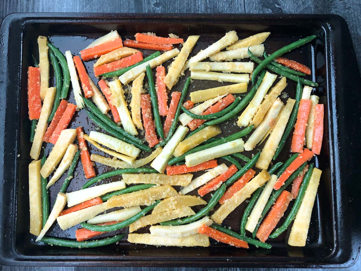 baking tray with raw vegetable pieces with garlic and parmesan ready to bake