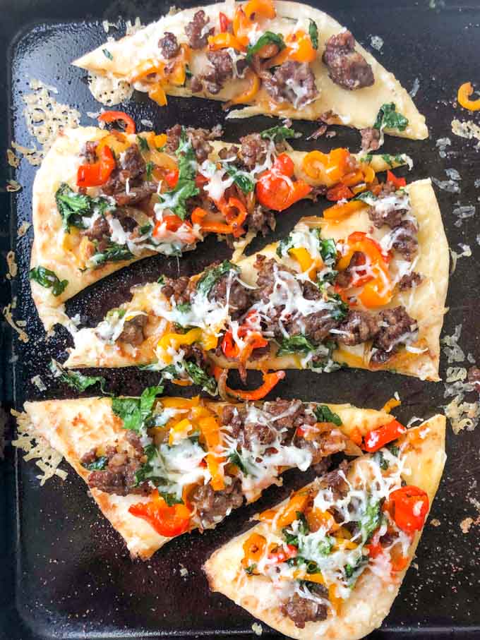 cookie sheet with asiago, sausage and pepper flatbread pizza cut up