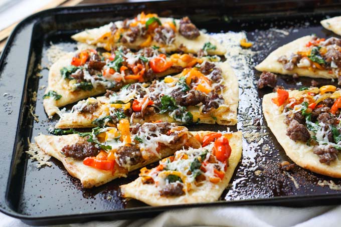 cookie sheet with asiago, sausage and pepper flatbread pizza cut up