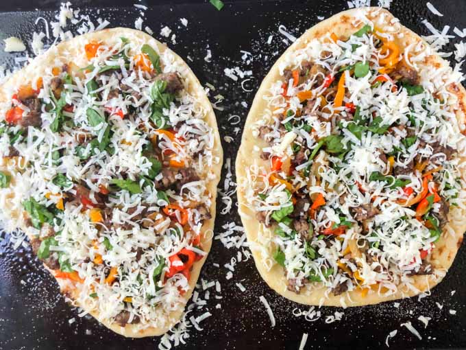 cookie sheet with asiago, sausage and pepper flatbread pizza ready to bake