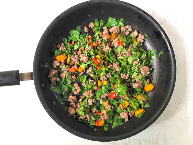 skillet with burrito filling of sausage, peppers and onions