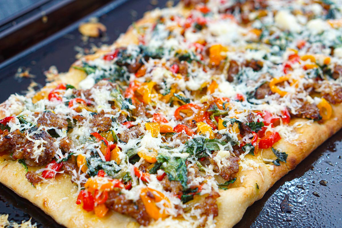 Closeup of a the tay with the finished Italian sausage flatbread ready to cut.
