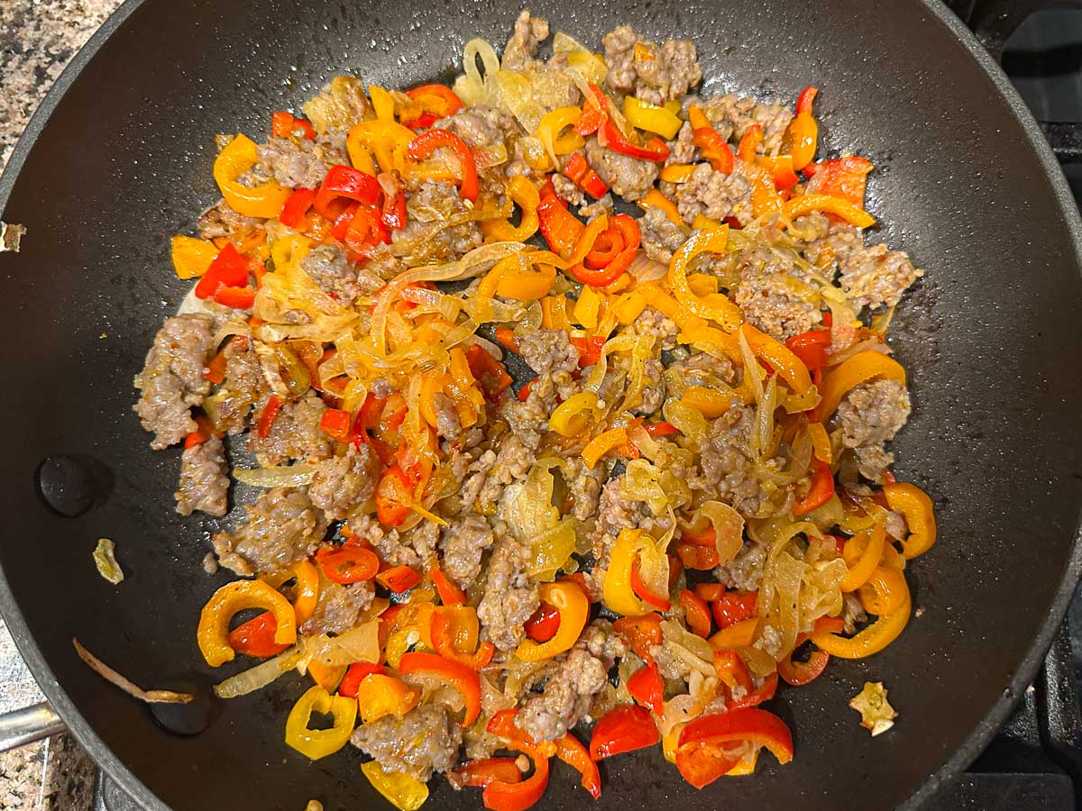 Skillet with sautéed onions and sausage.