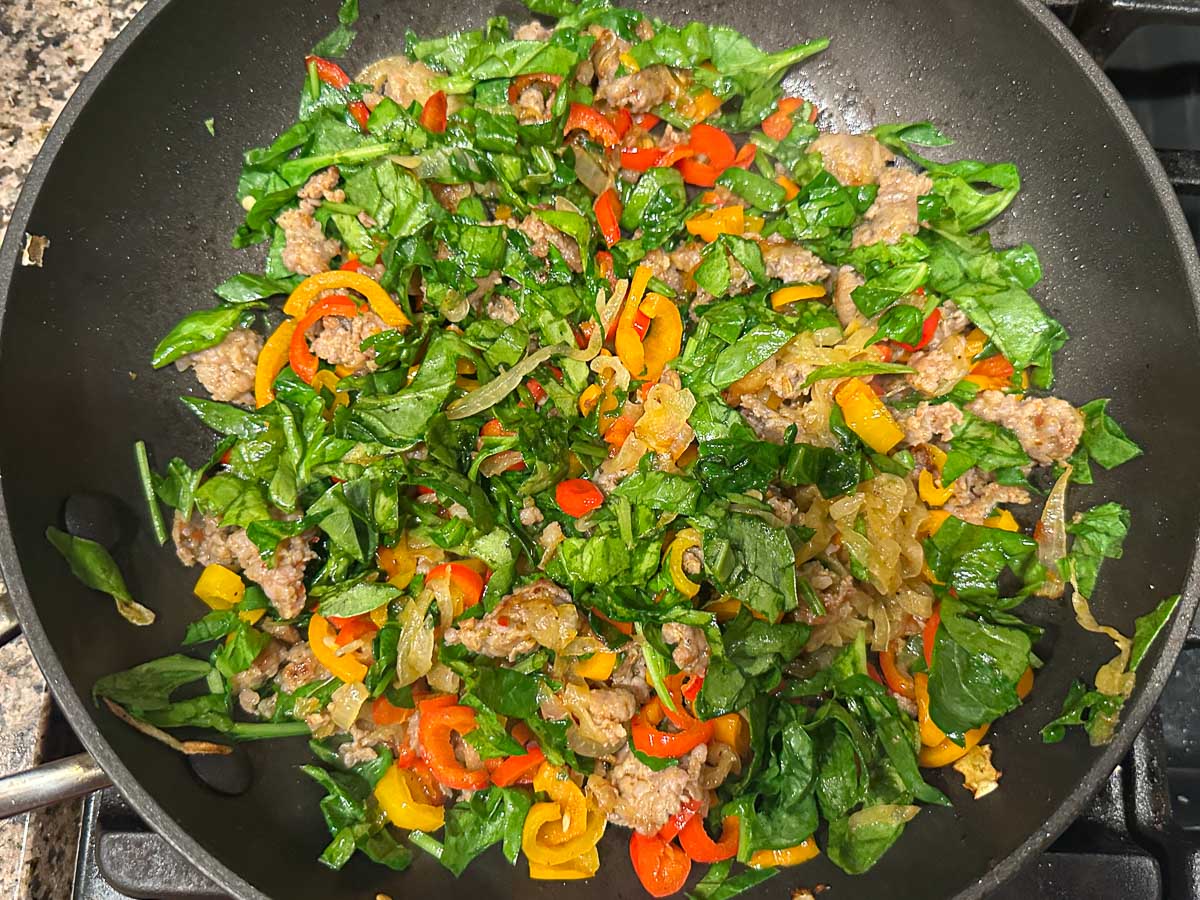 Skillet with spinach added to the pan.