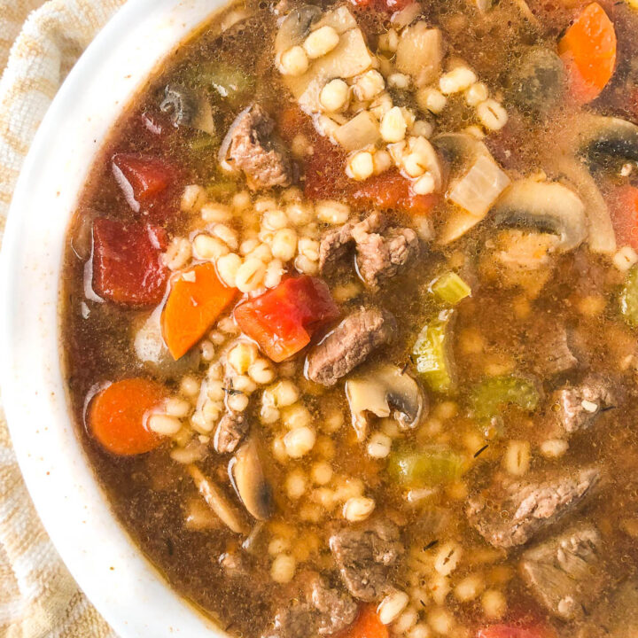 closeup of a white bowl with beef and barley soup