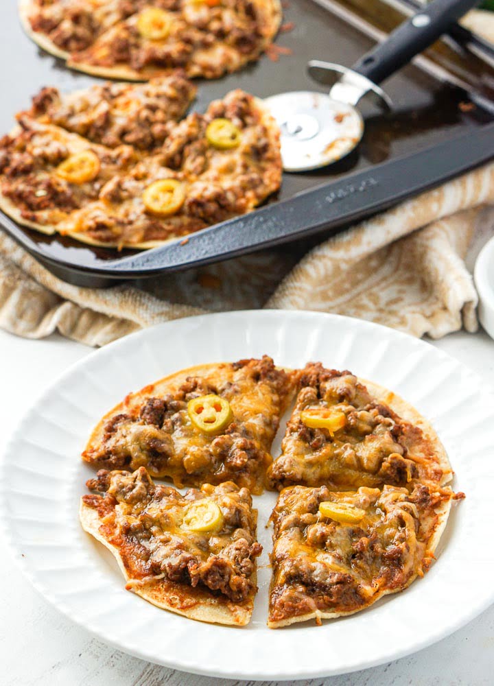 closeup of white plate with beef nachos and a cookie sheet in the background