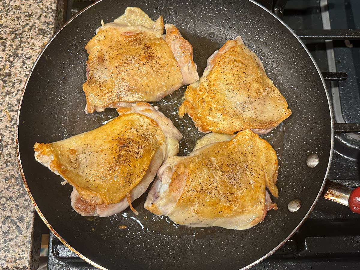 frying pan with browned thighs
