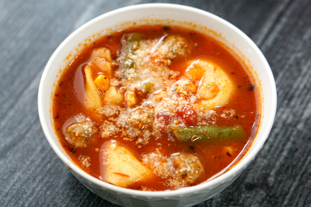 white bowl with Italian meatball and veggie soup with parmesan on top