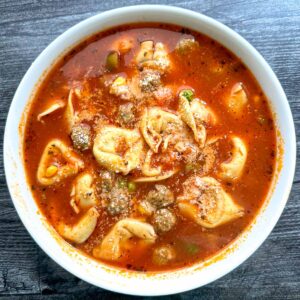 aerial view of white bowl with meatball tortellini soup