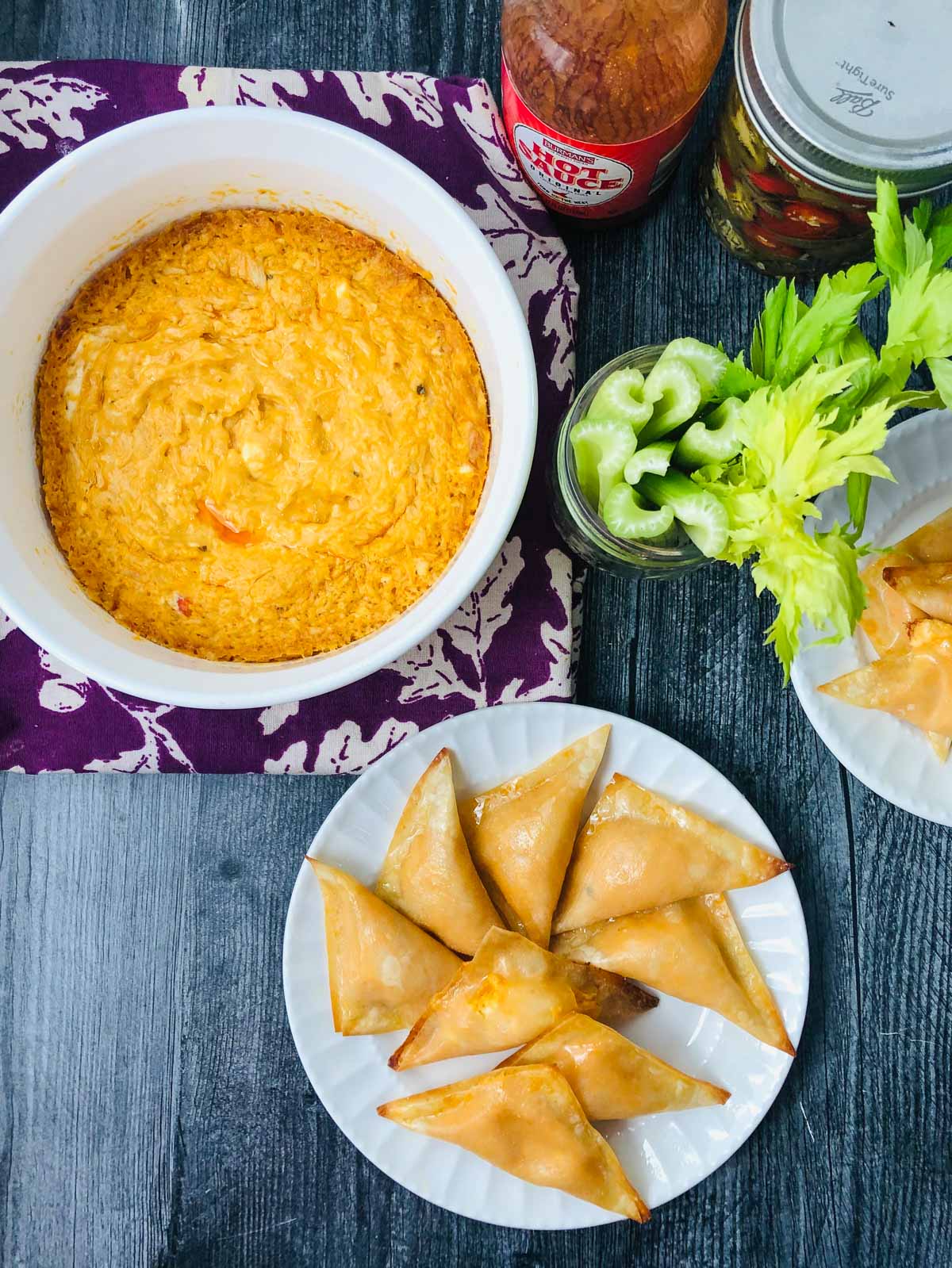 aerial view of bowl of buffalo dip and white plate with buffalo chicken wontons