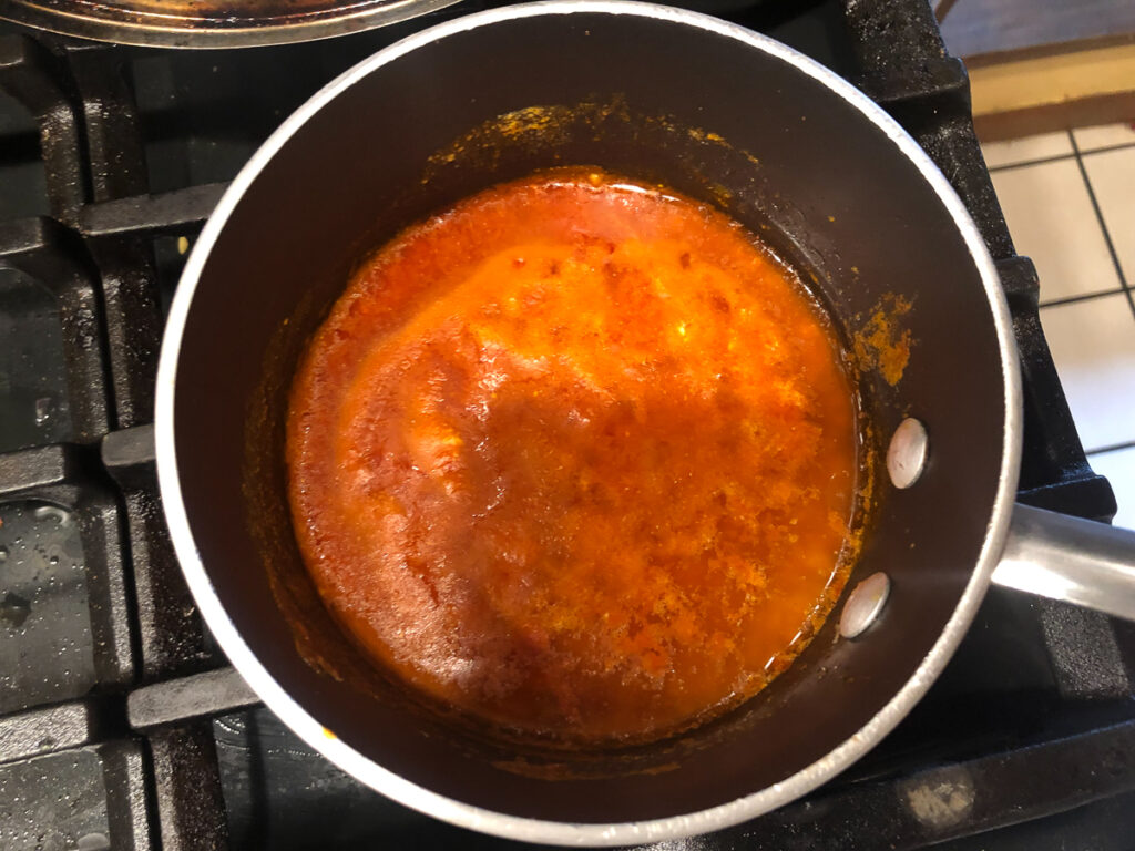 pan on the stove with buffalo hot sauce