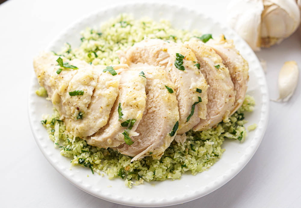closeup of a white dish with cauliflower rice and a piece of lemon chicken on top