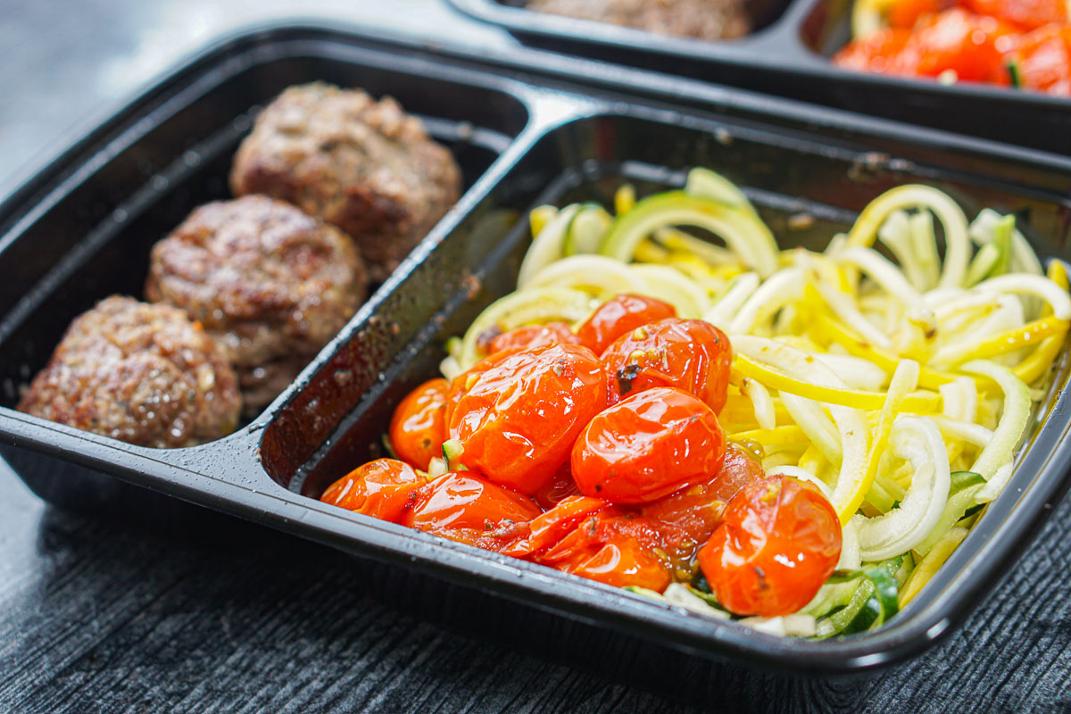 closeup of homemade freezer meal with meatballs, zucchini noodles and roasted tomatoes