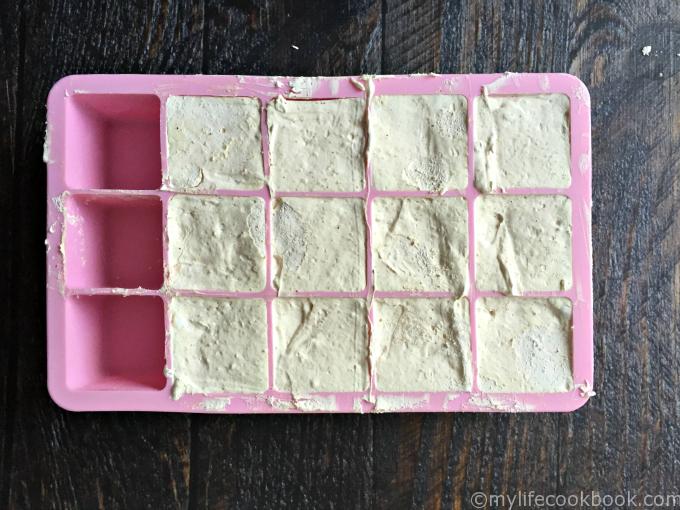 Silicone pink ice cube tray with peanut butter mixture in it.