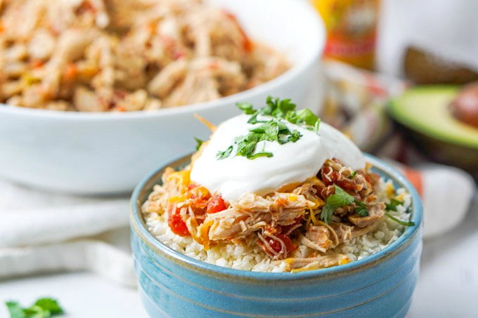 blue bowl with cauliflower rice and slow cooker salsa chicken with white bowl in background