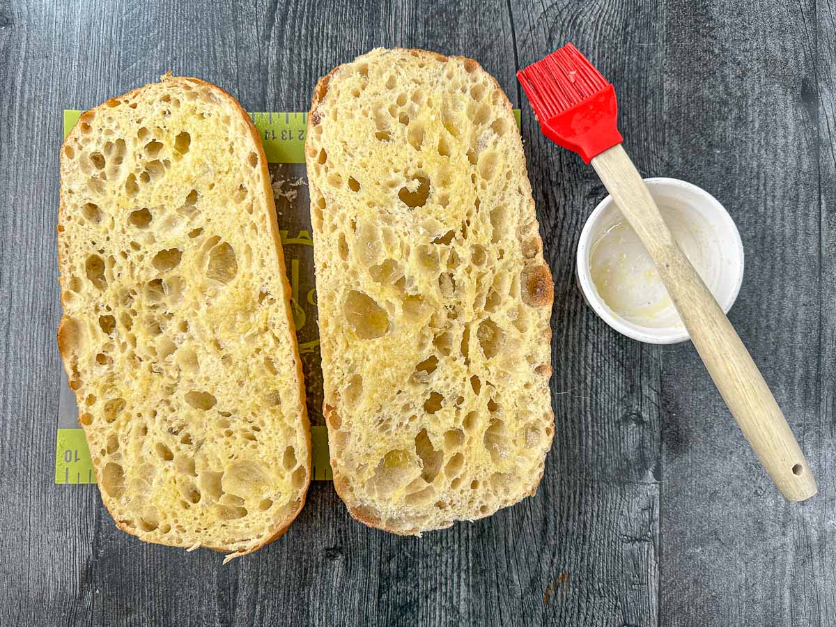 loaf of bread cut in half with olive oil brush