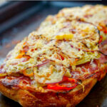 baking tray with cooked antipasto pizza on French bread that was baked and text