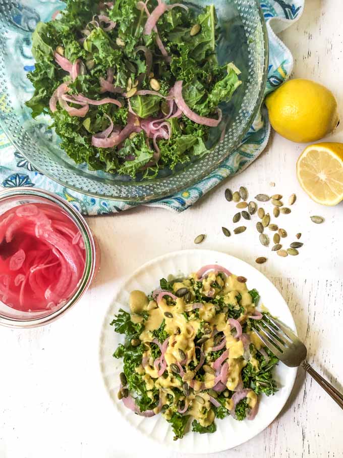 aerial view of kale salad bowl, pickled onions, pepitas and lemons