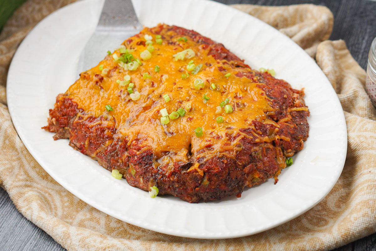 white platter with baked taco meatloaf with melted cheese