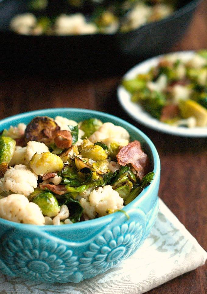 Long photo with blue bowl of brussels sprouts bacon and cauliflower.