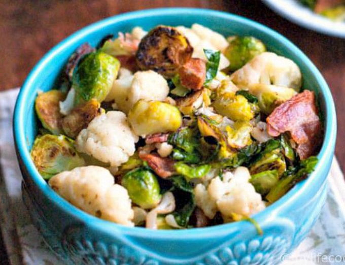 A blue bowl with Brussels sprouts and bacon and cauliflower.