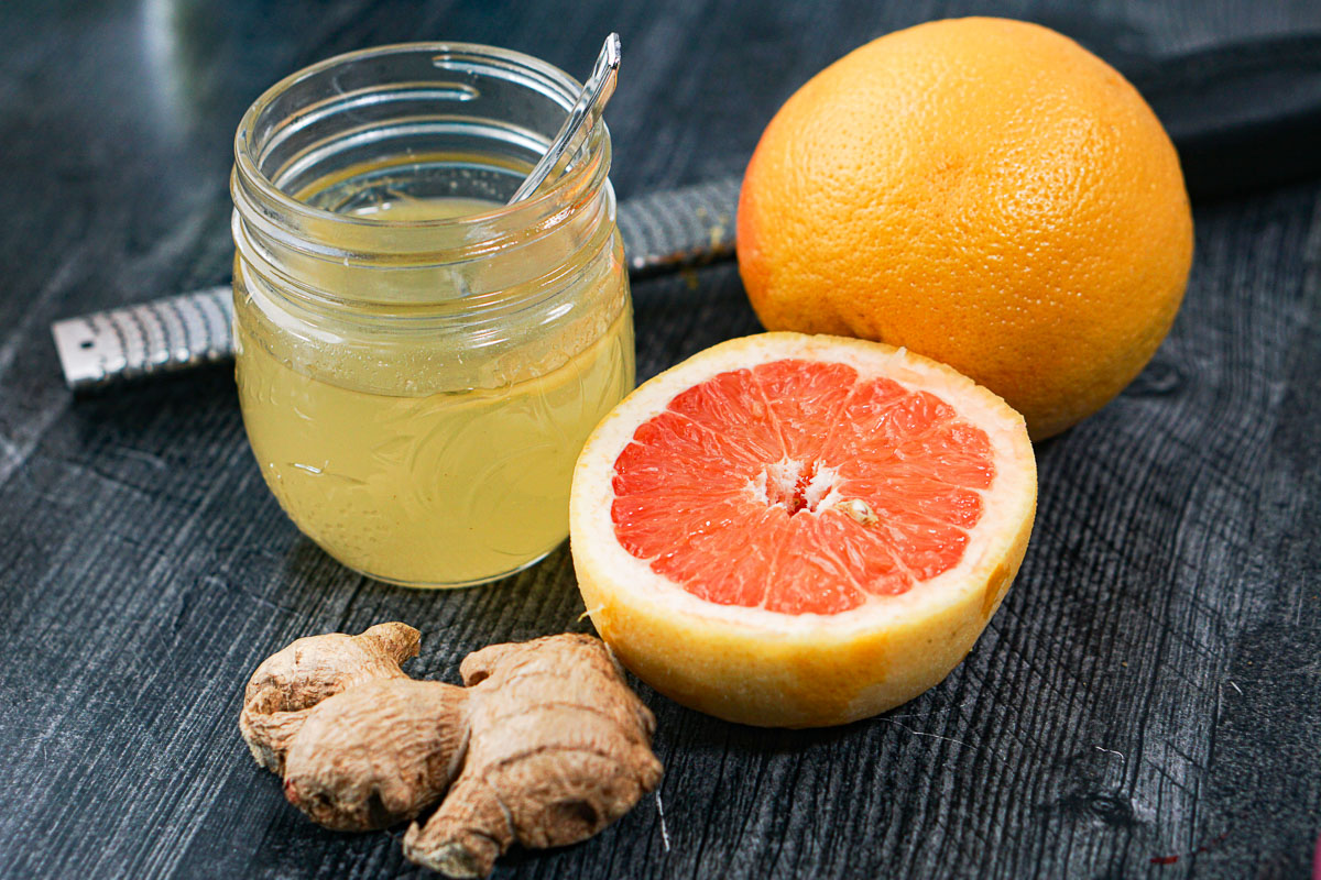 jar with simple syrup and fresh grapefruits and fresh ginger root