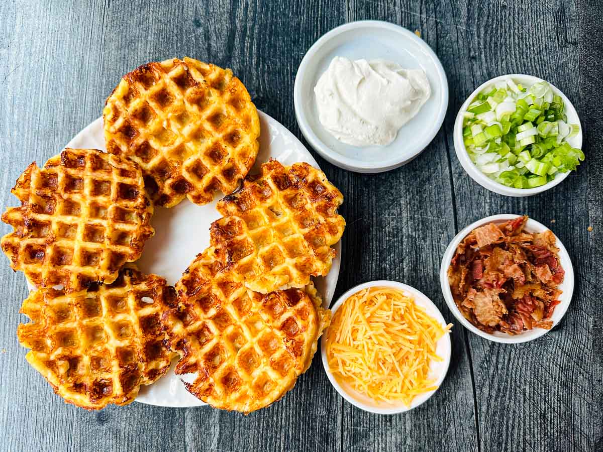 plain potato waffles on white plate and toppings surrounding them