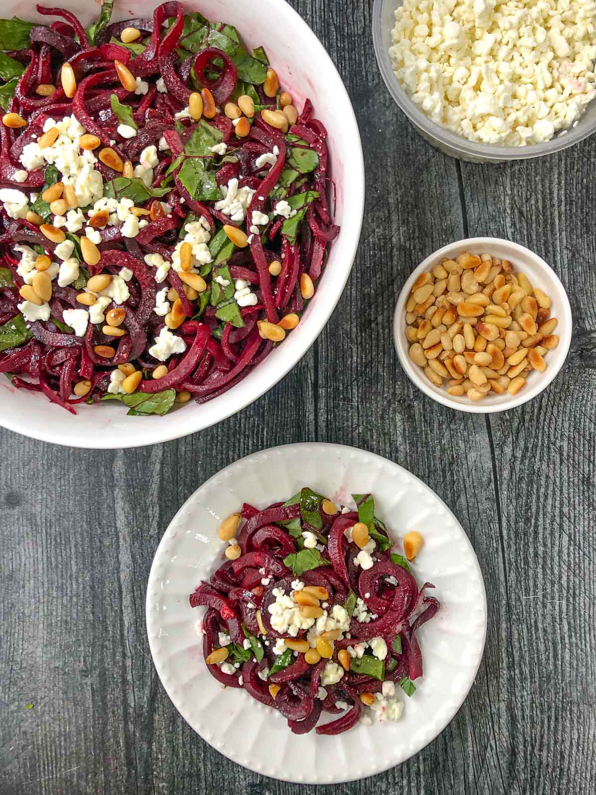 aerial view of a bowl and plate with beet noodle salad with goat cheese and toasted pine nuts