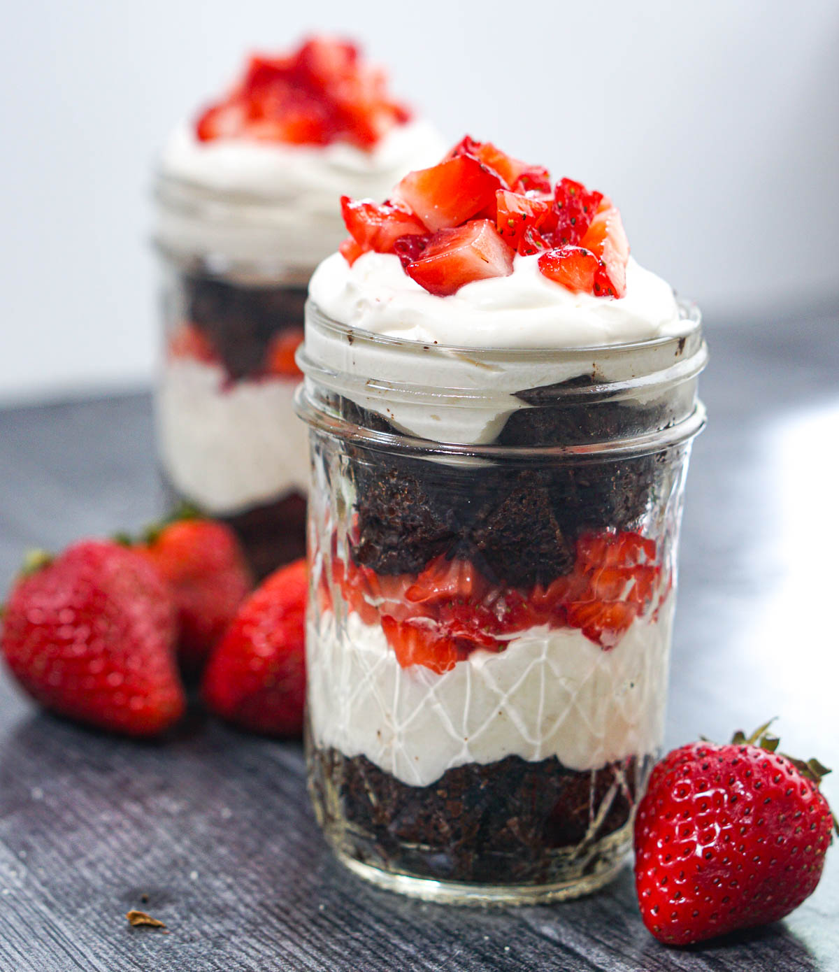 Closeup of 2 jars filled with strawberries and chocolate keto cheesecake parfaits.