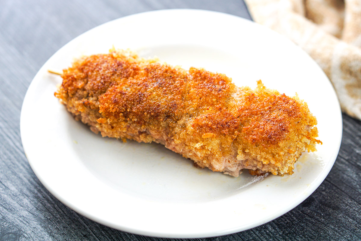 white plate with a fried breaded pork cube skewer