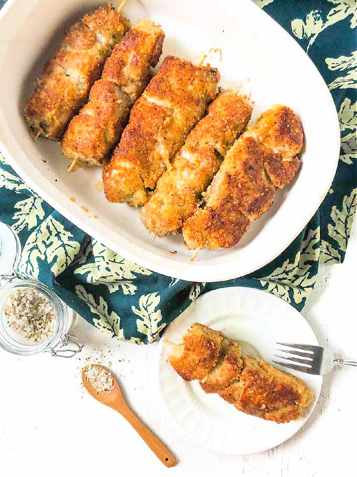 aerial view of a baking dish and plate with breaded pork skewers